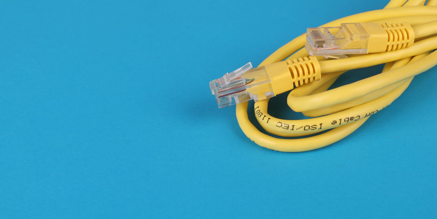 Gelbes Netzwerkkabel mit zwei transparenten Steckern auf blauem Hintergrund