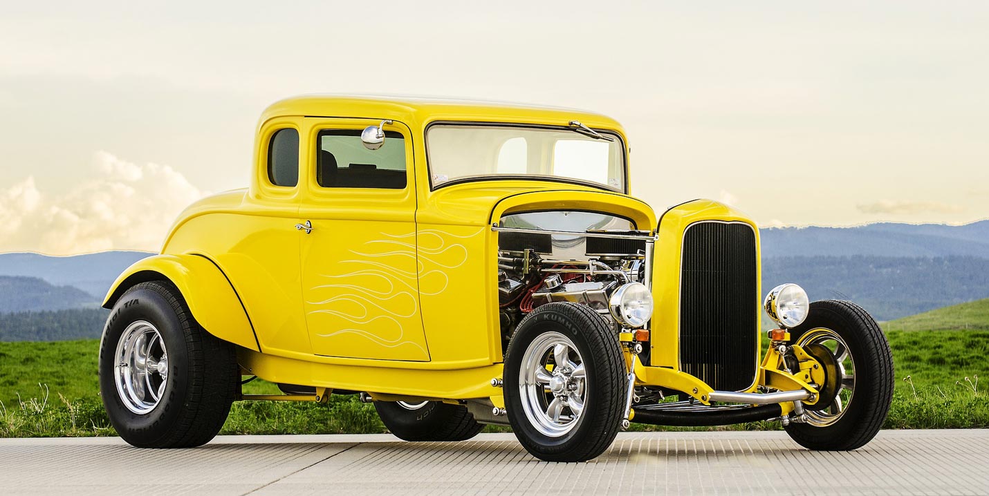 SEO verstehen – die Zusammenhänge hinter Sichtbarkeit Gelber Hot Rod mit freiliegendem Motor auf einer Straße vor grüner Landschaft und bewölktem Himmel
