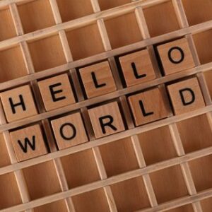 Holzbuchstaben in einem Setzkasten bilden den Schriftzug „HELLO WORLD“ auf zwei Zeilen