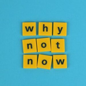 Gelbe Buchstabensteine mit dem Schriftzug „why not now“ auf blauem Hintergrund