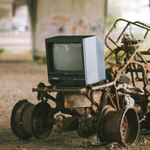 Alter Röhrenfernseher auf einer stark verrosteten Maschine mit Rädern