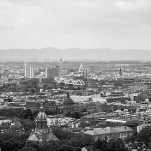 Schwarz-Weiß-Panorama einer dicht bebauten Stadt mit Häusern, Hochhäusern und Hügeln am Horizont