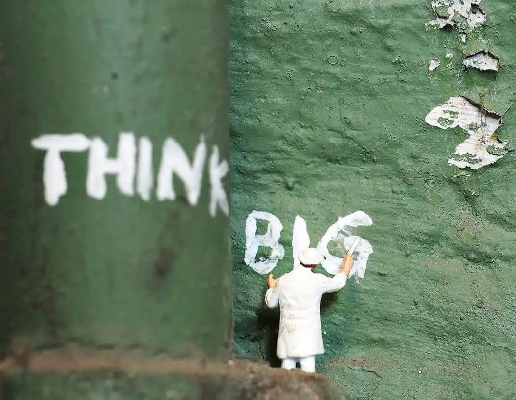 Miniaturfigur malt den Schriftzug BIG an eine Wand als Symbol dafür, dass der Erfolg einer Webseite durch Strategie, Design und klare Entscheidungen entsteht