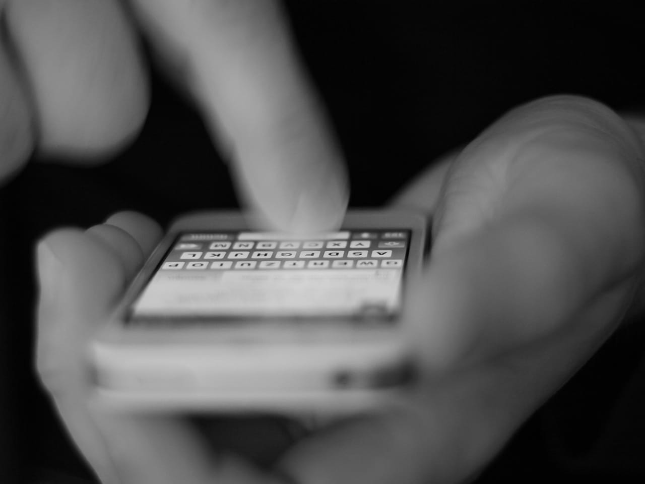 Hand bedient die Tastatur eines Smartphones als Symbol für die mobile Nutzung moderner Firmenwebseiten
