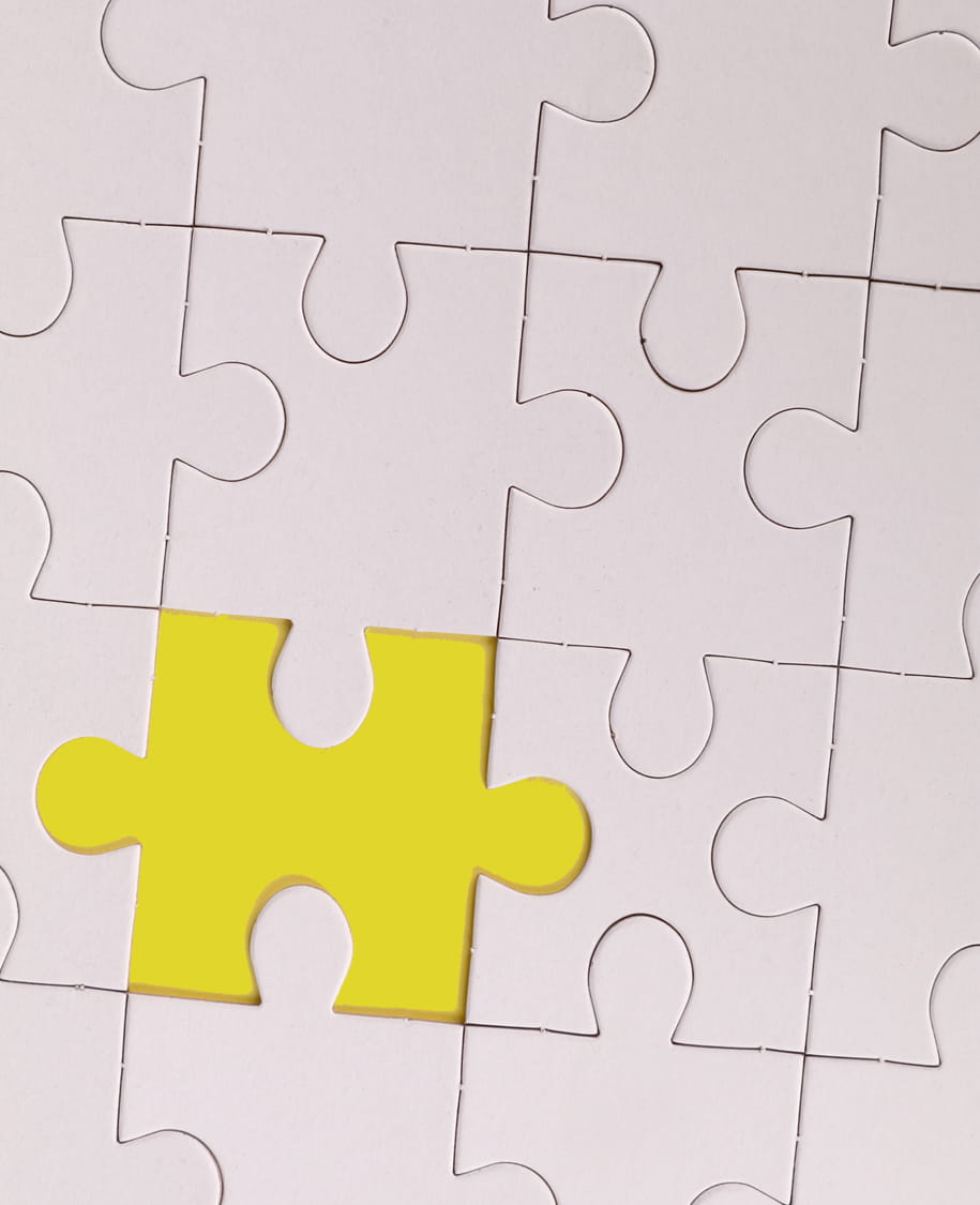 Ein gelbes Puzzleteil hebt sich zwischen mehreren weißen Puzzleteilen hervor
