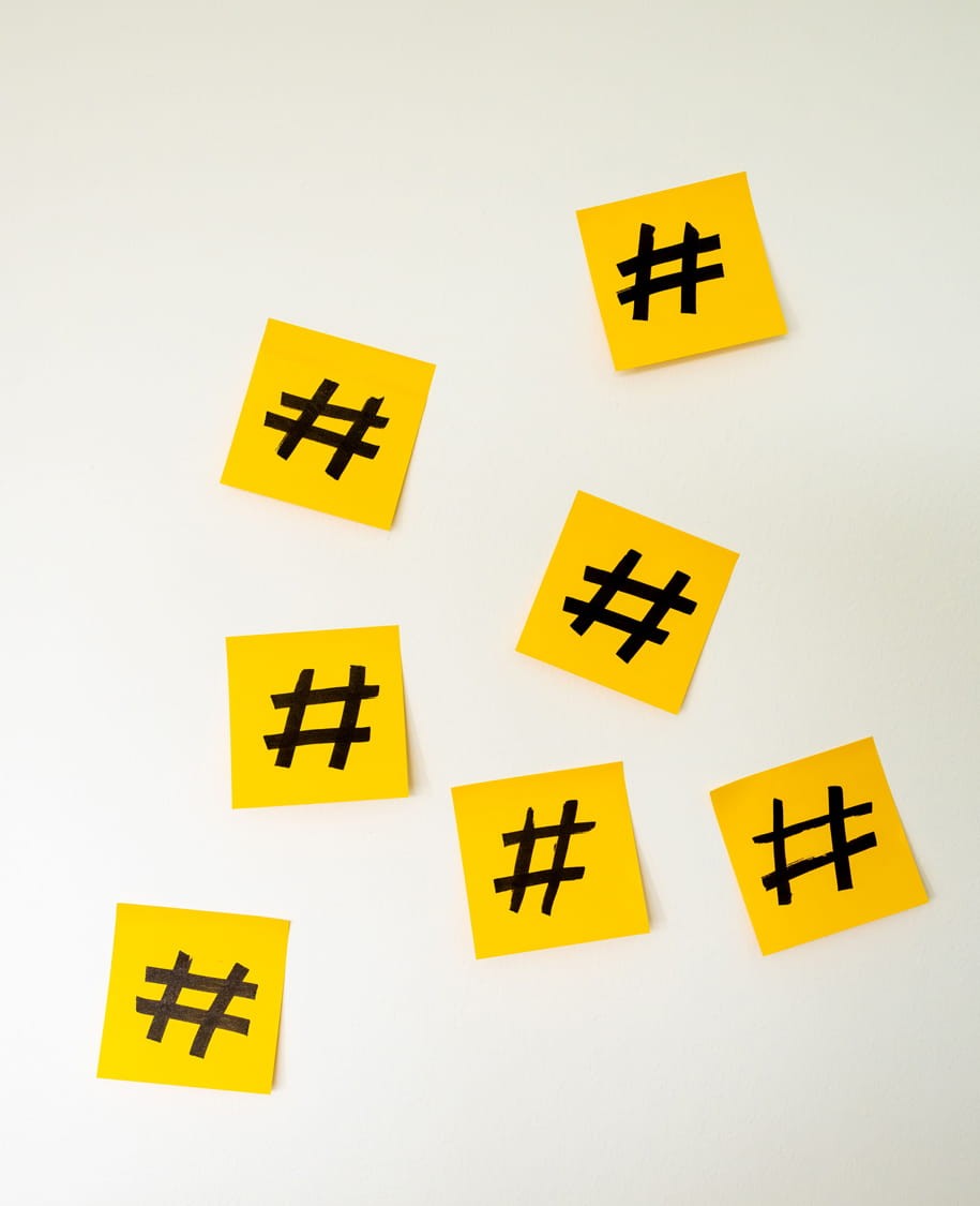 Mehrere gelbe Haftnotizen mit schwarzen Hashtag-Zeichen auf hellem Hintergrund.