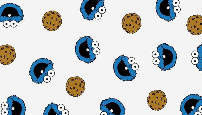 Wiederholtes Muster aus blauen Comic-Monsterköpfen und braunen Keksen auf hellem Hintergrund