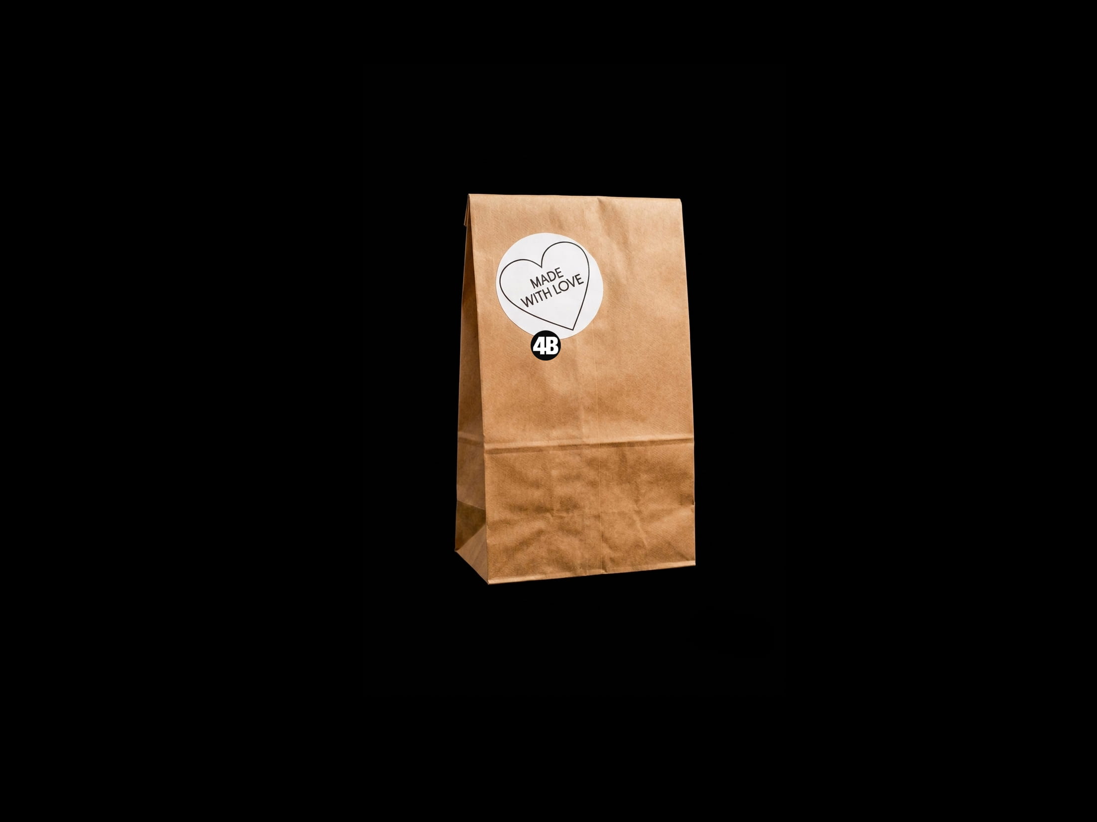 Made with love – die Webdesign-Signatur von 4Bullmann Braune Papiertüte mit einem herzförmigen „Made with love“-Aufkleber und dem 4B-Logo vor schwarzem Hintergrund.