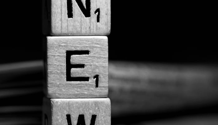 Schwarz-weiße Nahaufnahme gestapelter Holzbuchstaben mit den Buchstaben N, E und W