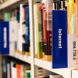 Bücherregal mit einem blauen Hinweisschild „Internet“ zwischen verschiedenen Fachbüchern