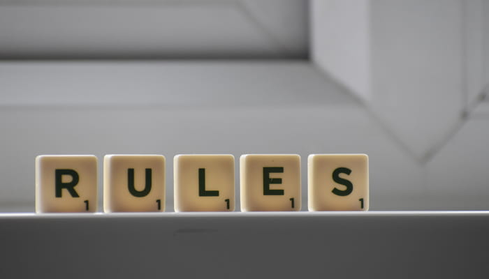 Fünf Buchstabensteine auf einer Ablage bilden das englische Wort „RULES“
