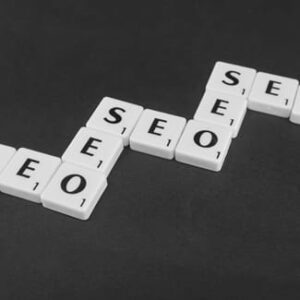 Weiße Buchstabensteine bilden mehrfach das Wort „SEO“ auf einem schwarzen Untergrund