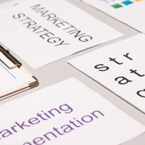 Bedruckte Karten mit den Aufschriften „Marketing Strategy“ und „Marketing Presentation“ liegen auf einem hellen Schreibtisch