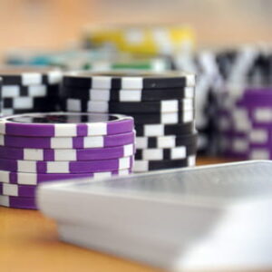 Gestapelte violette und schwarz-weiße Pokerchips stehen neben einem verdeckten Kartenstapel auf einem Tisch