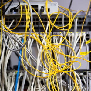 Gelbe und weiße Netzwerkkabel verlaufen vor den Anschlüssen eines Serverschranks