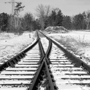 Verschneite Bahngleise führen durch eine Weiche und teilen sich in zwei unterschiedliche Richtungen